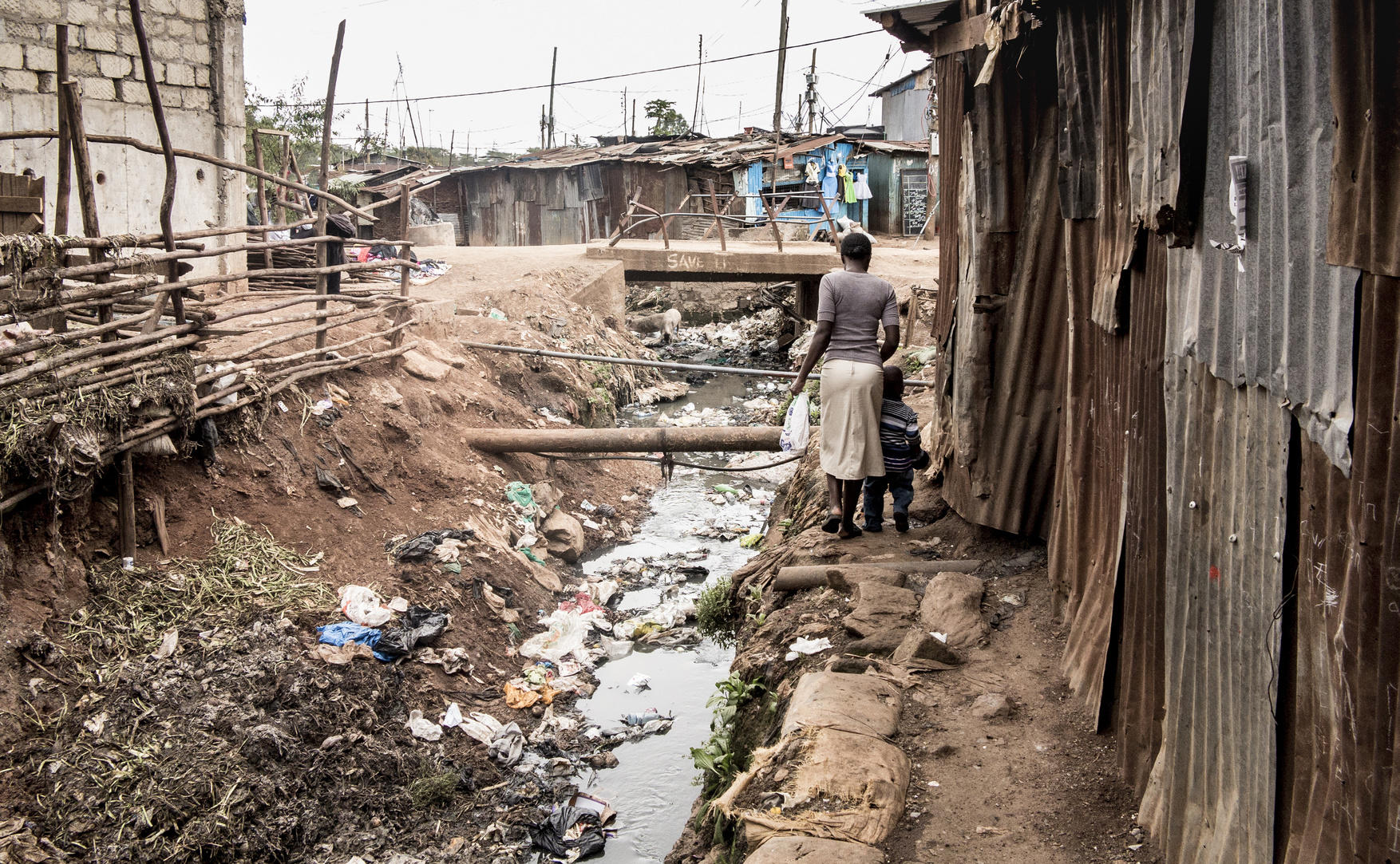 People walking along an open sewer in a slum in Africa © Wollwerth Imagery